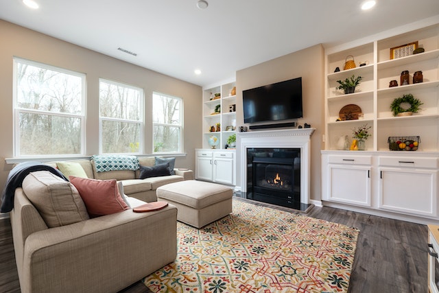 living room with three windows a white bookshelf and a linen couch